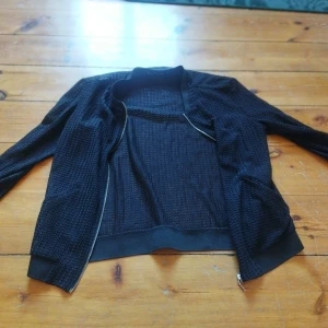 Svart cardigan jacka från Zara Basic - Snygg svart cardigan jacka från Zara Basic med ett diskret mönster. Jackan har dragkedja framtill och är långärmad. Perfekt för en stilren look.
