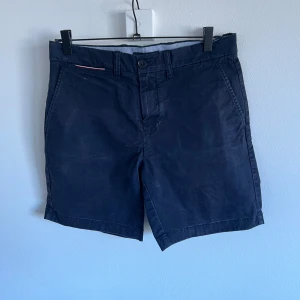 Mörkblå shorts från Tommy Hilfiger - Snygga mörkblå shorts från Tommy Hilfiger med klassisk design. De har en knapp och dragkedja framtill samt sidofickor. Perfekta för en stilren look.