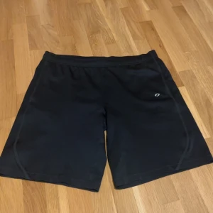 Svarta träningsshorts - Snygga svarta träningsshorts med elastisk midja och en liten logga på sidan. Perfekta för gymmet eller löprundan. De är gjorda i ett lätt och bekvämt material som andas.