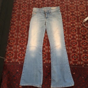 Blå bootcut jeans från Diesel - Snygga ljusblå bootcut jeans från Diesel med klassisk femficksdesign. Jeansen har en lätt slitning på framsidan och en bekväm passform. Perfekta för en avslappnad stil.