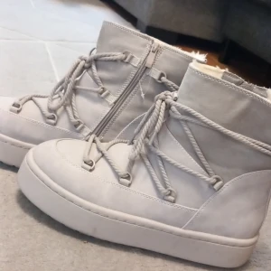 BON | Varmfodrade boots med snörning och dragkedja -  Använd en gång. Snygga beige boots med snörning och dragkedja på sidan. De har en hög sula och är fodrade med mjukt material för extra komfort. Perfekta för kyligare dagar. 