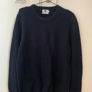 Mörkblå  stickad tröja från NN07 - Säljer en stilren mörkblå stickad tröja från NN07. Tröjan har en klassisk rund hals och långa ärmar, perfekt för kyligare dagar. Passar bra till både jeans och chinos. Ett måste i garderoben för en tidlös look. Säljer tröjan pågrund av att jag har vuxit ur den. Hör gärna av er kring funderingar!!