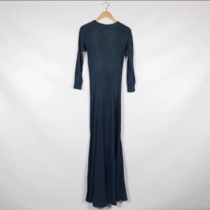 Mörkblå långklänning från Polo Ralph Lauren - Snygg mörkblå långklänning från Polo Ralph Lauren i ett ribbat material. Klänningen har långa ärmar och en rund halsringning, perfekt för en stilren look. Passar utmärkt för både vardag och speciella tillfällen.