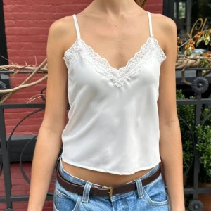 vitt linne med spetsdetaljer (brandy melville) - säljer ett vitt linne från brandy melville med spetsdetaljer längs halsringningen. linnet har jättemjukt & glansigt tyg🫶🏻🤍   (ord. pris: 265kr)