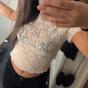 Vit spetsblus - Säljer en söt vit spetsblus med korta ärmar och croppad passform. Perfekt för en somrig look eller att styla med lager. Blusen har ett vackert blommönster och är lätt och luftig.