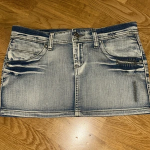 Jeanskjol från Inside Girl - Snygg jeanskjol från Inside Girl i storlek 38. Kjolen har en klassisk blå denimlook med slitna detaljer och dekorativa nitar på fickorna. Perfekt för en avslappnad stil.