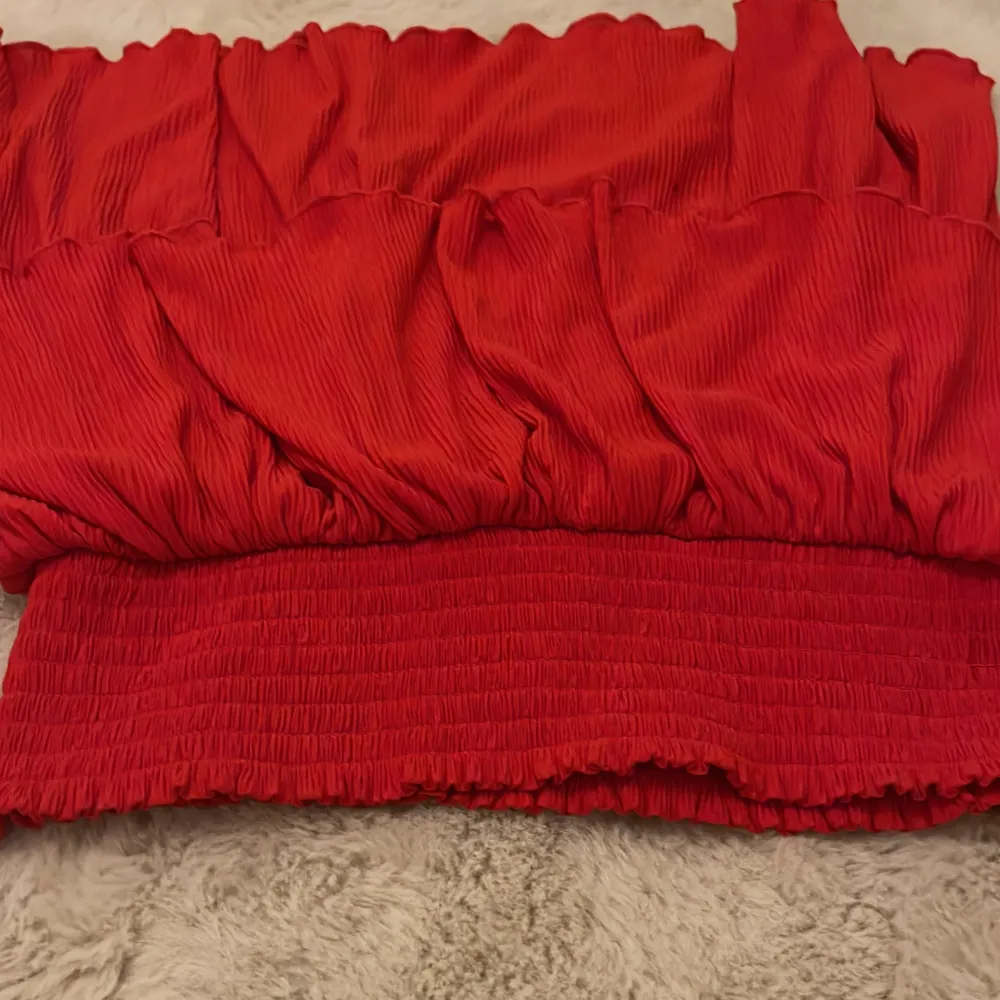 Snygg röd volangkjol från Kappahl med elastisk midja. Perfekt för att ge en färgklick till din outfit. Kjolen har en härlig volangdetalj som ger extra volym och rörelse.. Hameet.