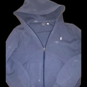 Blå huvtröja från Polo Ralph Lauren - Säljer en blå huvtröja från Polo Ralph Lauren snöret till luvan kan jag packa med om så viljas. dragkedja och broderad logga på bröstet lite sliten i slutet på armarna men inget som märks. Pris kan diskuteras vid snabb affär👍