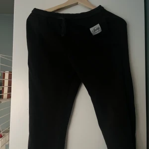 Svarta mjukisbyxor från Frank Dandy - Säljer ett par svarta mjukisbyxor från Frank Dandy. Byxorna har en elastisk midja med snörning för justerbar passform. Perfekta för en avslappnad stil.