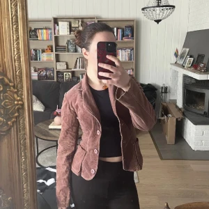 Brun manchesterjacka från Savann - Snygg brun manchesterjacka från Savann. Jackan har en klassisk krage och knäppning framtill med två knappar. Perfekt för höst och vår med sin mjuka och bekväma passform.