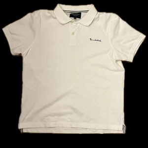 Vit pikétröja från Bondelid - Säljer en stilren vit pikétröja från bondelid med korta ärmar och klassisk krage. Tröjan har en broderad logotyp på bröstet och knappar vid halsen. Perfekt för en avslappnad och snygg look. Tröjan är använd 1 max 2 gånger och är helt i nyskick!