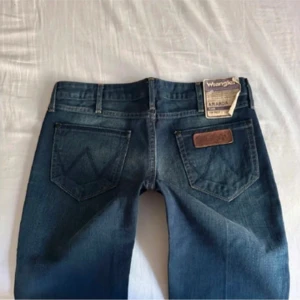 Lågmidjade bootcut jeans Wrangler  - Supersnygga blå bootcut jeans från Wrangler med läderdetalj på bakfickan! Köpta av en tjej från Plick med lappen kvar. Passade tyvärr inte mig då de är väldigt små i storleken💕💕Innerbenslängd: ca 85 cm, Midjemått: ca 40 (bilderna är lånade) Jag skulle snarare säga att dessa jeans sitter bra på storlek 26-27, då jag vanligtvis har storlek 28-29, men de är väldigt tajta i låren. Bara att säga till för fler mått🥰Köpta för 650kr!