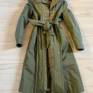 Ny jacka från Colmar stl S -  Fin lång täckjacka från Colmar som aldrig har kommit till användning.Fast vadderad väst med huva. Italiensk stl 42 som kan passa både S och M Färg mud green. Finns i Bandhagen alt skickas . Köparen står för frakten.