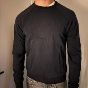 Navy Blue hoodie från Armani Jeans - Snygg svart tröja från Armani Jeans med ett upphöjt logotyptryck på framsidan. Tröjan har långa ärmar och en klassisk rund halsringning. Perfekt för en stilren look. Nypris: ~1500. Mitt pris; 399.
