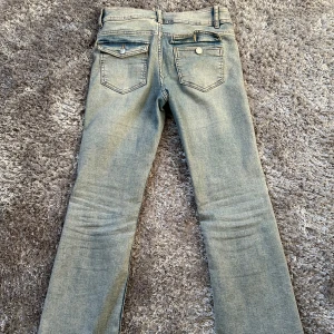 Blåa lågmidjade bootcut jeans  - Snygga blå jeans från Kappahl med klassisk femficksdesign och knappgylf. Perfekta för en avslappnad stil. De har en rak passform och är tillverkade i slitstarkt denim.
