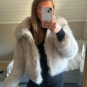 Beige pälsjacka - Säljer en fluffig och trendig beige pälsjacka med långärmad design. Jackan har en oversized passform och är perfekt för kyligare dagar. Den ger en lyxig känsla och är lätt att matcha med olika outfits.