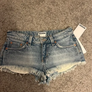 Blå jeansshorts med fransar från Weekday - Säljer ett par trender jeansshorts från weekday aldrig använda och prislapp fortfarande på