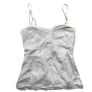 Vintage Vit spetsdetaljerad linnetopp  - Söt vit spets bomull topp. Strl 38 men mer en S i storlek. Har knytning där bak. Dragkedja på sidan.