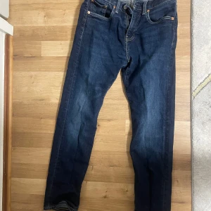 Levi's 502 mörkblå jeans - Mörkblå jeans från Levi's Premium, modell 502. Klassisk femficksdesign med raka ben och orange sömmar. Skinnpatch bak i midjan och röd Levi's-tagg på bakfickan. Perfekta för en stilren vardagslook.