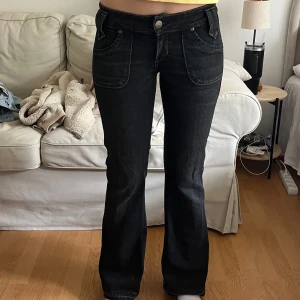 Svarta bootcut jeans från Lee - Snygga svarta jeans från Lee med bootcut passform. Lågmidjade som har coola fickor. Storlek w28. Slitningar nertill. 