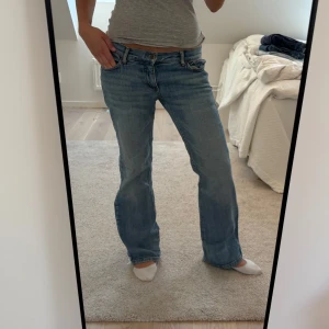 Ljusblå bootcut jeans - Säljer ett par ljusblå jeans med bootcut passform och klassisk femficksdesign. Jeansen har normalhög midja och är tillverkade i denim. Perfekta för dig som gillar en avslappnad men ändå snygg stil.