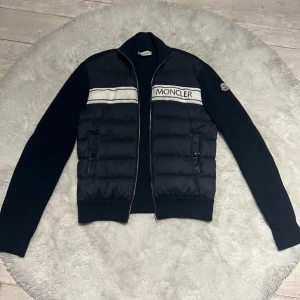  Moncler cardigan  - Moncler cardigan i fantastisk skick. Lite flaw på axeln men som på bild är den lagad så syns knappt vid användning. Cardiganen passar någon mellan 175-185.
