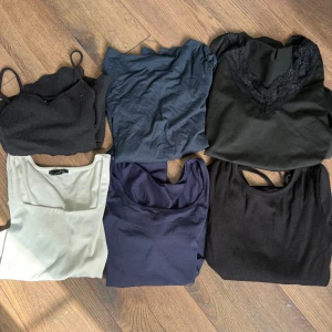 Mix av toppar i olika färger och modeller - Säljer ett set med sex olika toppar i svart, blått, vitt. Blandningen innehåller både linnen och t-shirts, vissa med smala axelband och andra med kort ärm. En tröja har spetsdetalj vid halsen och en är croppad.