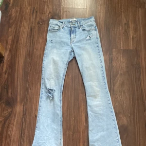Ljusblå bootcut jeans från Perfect Jeans - Ljusblå jeans med bootcut passform från Perfect Jeans. Byxorna har slitna detaljer vid fickan och på ena benet, klassisk femficksmodell och normalhög midja. Orginalpris: 500kr