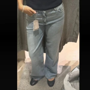 Ljusblå wide leg jeans - Säljer ett par ljusblå jeans med breda ben och normal passform. Jeansen har klassisk femficksdesign, knapp och dragkedja framtill. Perfekta för en avslappnad och trendig look.