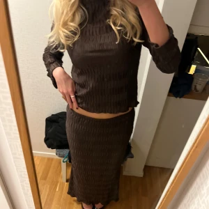 Brunt set, Gina Tricot - Brunt tvådelat set med långärmad topp och matchande lång kjol. Båda delarna har ett vågigt mönster. Toppen har en lite högre hals💞💞