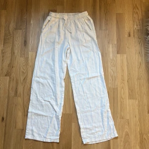 Vita linnebyxor från Lindex - Säljer ett par vita linnebyxor från Lindex med dragsko i midjan och raka ben. Byxorna har sidfickor och är perfekta för en avslappnad stil. Lätta och luftiga, passar bra till varma dagar.