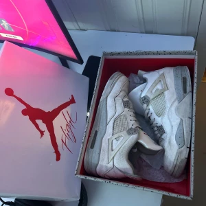 Vita Nike Air Jordans 4 - Säljer ett par klassiska vita Nike Air Jordans 4 med meshdetaljer och ikonisk siluett. Skorna har snörning och platt sula, perfekt för dig som gillar streetwear och sneakers med retrovibbar. Använda ganska mycket därav lågt pris.