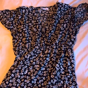Svart blommig klänning  - Säljer denna klänningen ifrån new yorker. Det var ett tag sen den användes och har använts fåtal gånger. 