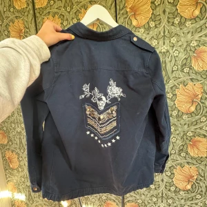 Mörkblå jacka med broderi och paljetter från Giminy - Säljer min mörkblåa vårjacka som jag köpte i Sthlm förra året men den ser ut som ny☺️ Den har ett unikt broderi med paljettdetaljer och blommor på ryggen, nypris 1200 priset kan diskuteras🥰