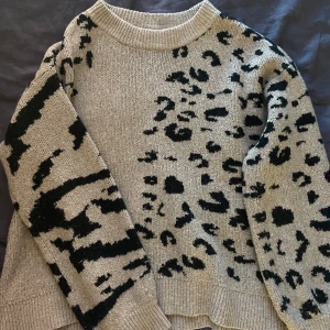 VILA Beige stickad tröja med leopardmönster - Säljer en beige stickad tröja med svart leopardmönster. Tröjan har rund halsringning och långa ärmar. Perfekt för dig som gillar djurmönster och vill ha en mysig och trendig look. Ifrån Vila