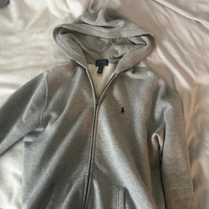 Grå hoodie från Polo Ralph Lauren - Polo ralph lauren kofta som har inte används mycket. Den är äkta, köpt för 1200kr och jag säljer den för 500.