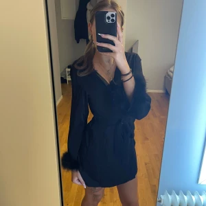 Tunn morgonrock med fluff  - Säljer en svart kort morgonrock med långa ärmar och fjäderdetaljer vid ärmsluten.  