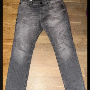 Jack and Jones slim glenn - Säljer ett par grå jeansbyxor med klassisk femficksdesign och raka ben. Byxorna har knapp och dragkedja framtill samt diskreta sömmar på bakfickorna. Perfekta för en avslappnad stil. Använda tre gånger. Storlek 32/30