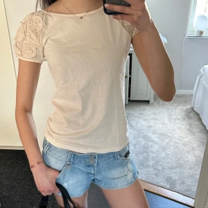 Kortärmad blus - Hej! Jag säljer den här jättesöta blusen med 3D blommor på ärmarna som passar perfekt till sommaren! Den har några få pyttesmå lagningar längst ner därav priset. Toppen passar en xs-s. Tveka inte att skriva vid frågor och pris kan diskuteras🤗