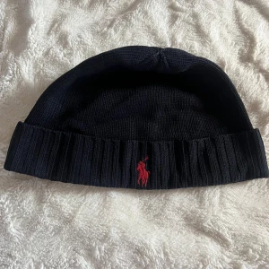 Marinblå stickad mössa från Polo Ralph Lauren - Säljer en marinblå mössa (Herrmodell) från Ralph Lauren. Mycket bra skick