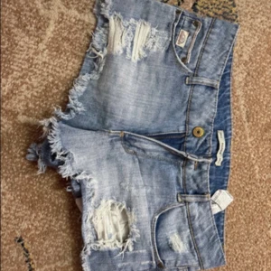 Blå jeansshorts med fransar från Pull&Bear - Snygga blå jeansshorts med fransig kant och slitna detaljer framtill. 