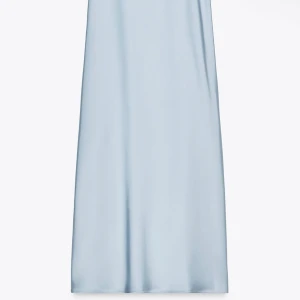 Ljusblå långklänning med v-ringning - Elegant ljusblå långklänning med v-ringad hals och korta, vida ärmar. Klänningen har en mjuk, svepande siluett och är tillverkad i ett glansigt material som ger en lyxig känsla. Perfekt för speciella tillfällen.