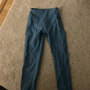 Blå träningstights från Relode - Säljer ett par blå träningstights från Relode med hög midja. Perfekta för gymmet eller löprundan, med stretchigt material som ger bra rörelsefrihet. Snygg och enkel design.