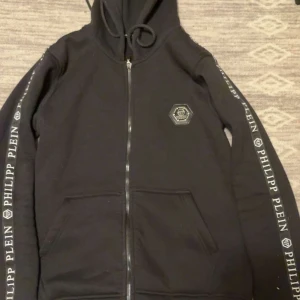 Svart hoodie från Philipp Plein med dragkedja - Svart hoodie från Philipp Plein med dragkedja framtill och huva. Äkta 