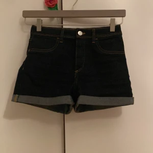 Mycket blåa  jeansshorts med uppvik - Snygga mörkblå  jeansshorts med klassisk femficksdesign och uppvikta benslut. Shortsen har normal passform och stängs med knapp och dragkedja. Perfekta för sommaren och enkla att matcha med olika toppar.