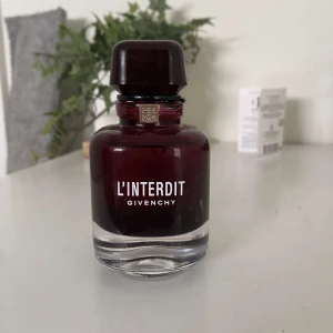 Givenchy - L'Interdit Eau de Parfum från Givenchy i en elegant mörkröd glasflaska med svart lock. Parfymen är tillverkad i Frankrike och rymmer 80 ml. Flaskan har en lyxig och modern design med tydlig Givenchy-logga framtill. 78/80ml