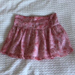 Rosa mönstrad kortkjol - Supersöt rosa minikjol. Kjolen är gjord i ett tunt, luftigt material som passar perfekt till varma dagar. Säljer på grund av att den är för liten. Säg till vid minsta fråga💞