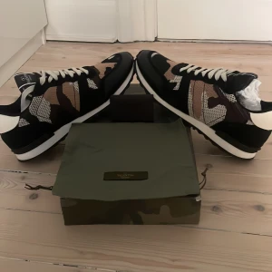 Valentino Rockrunners - Säljer ett par Valentino Rockrunner sneakers med snyggt camouflage-mönster i svart, beige, brunt och vitt. Materialmix av mocka och textil. Perfekta för dig som vill sticka ut med exklusiva sneakers till sommaren och du får med dust bag och kuvert från valentino  10/10 skick har använt skorna en gång inomhus skriv till mig om ni har några frågor