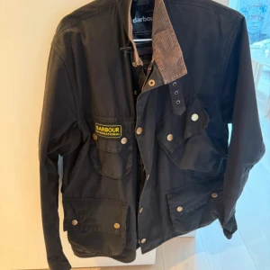 Svart vax  jacka från Barbour International  - Bra skick, ett mindre hål på tyget på insidan (se bild) men inget som syns utanpå.  Storlek S  Nypris 4999:-