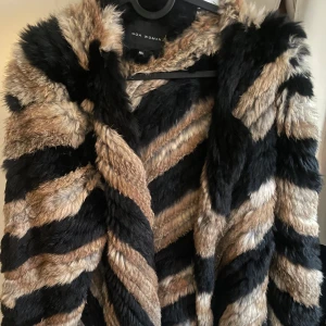 Unik pälsjacka i svart och vit - Säljer en fluffig och trendigpälsjacka från GOA Woman i storlek M/L. Jackan har ett zebrainspirerat mönster i svart, beige och brunt. Perfekt statement-plagg för dig som vill sticka ut.